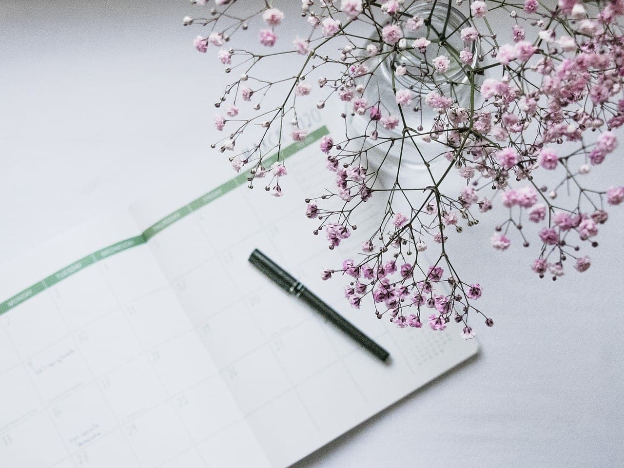 A physical calendar planner open on a desk next to a cup of coffee