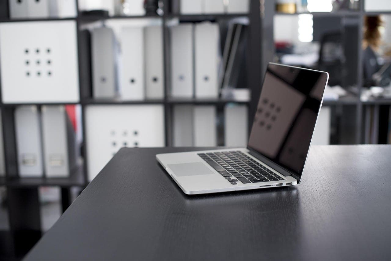 A messy office desk with a laptop displaying charts