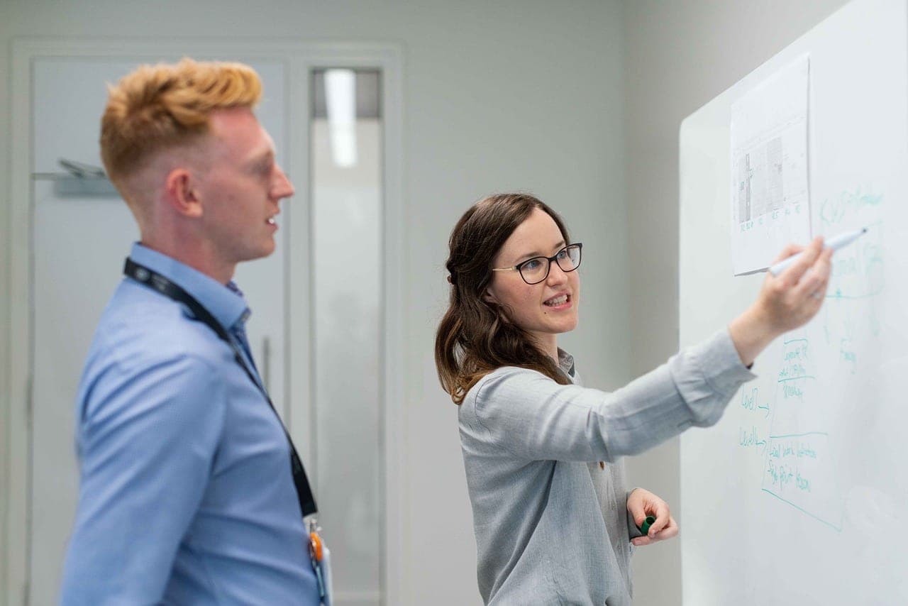 A whiteboard in a meeting room with complex entity relationship diagrams drawn on it.